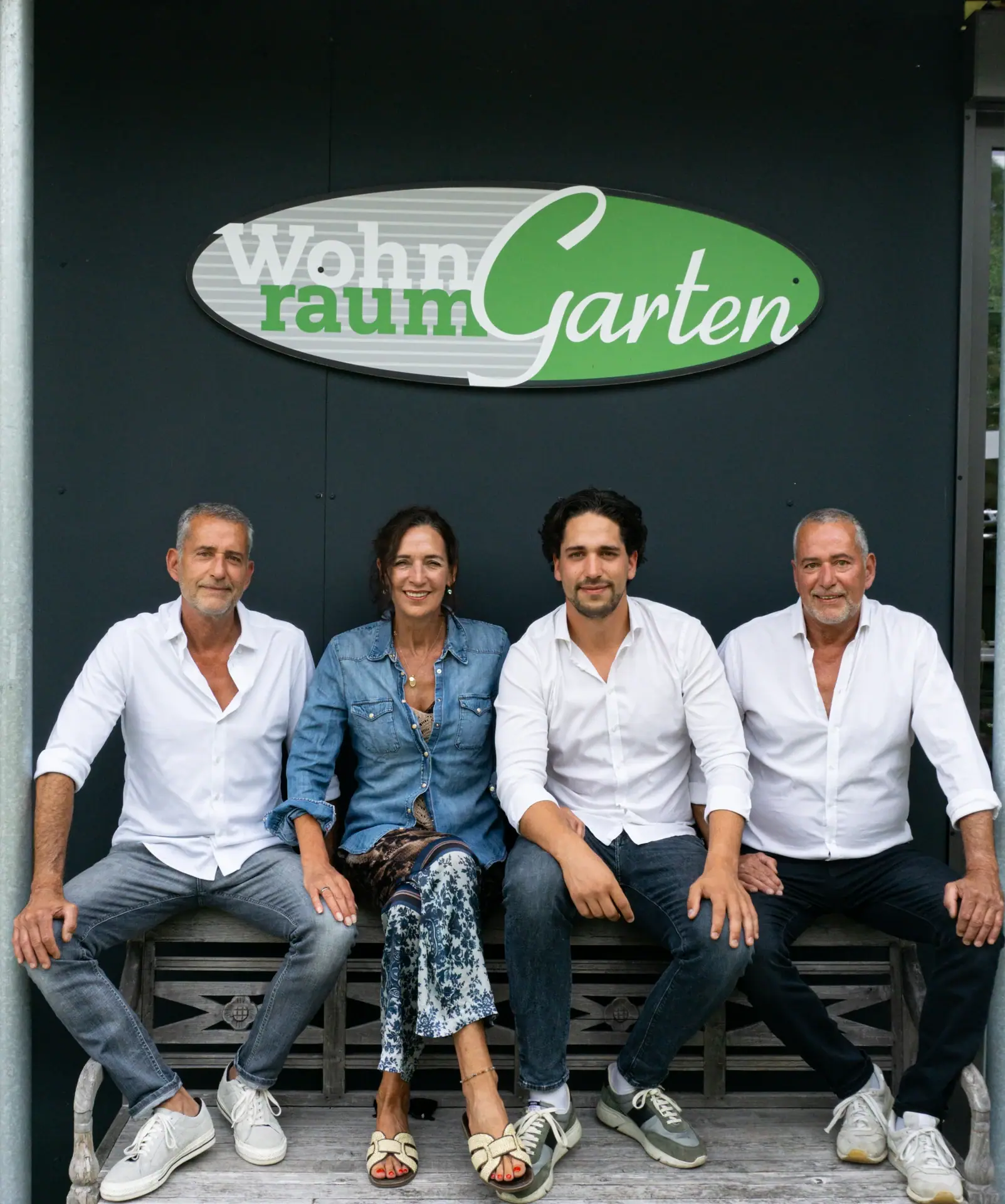 Das Team von WohnraumGarten aus Ravensburg auf einer Bank vor dem Firmenlogo