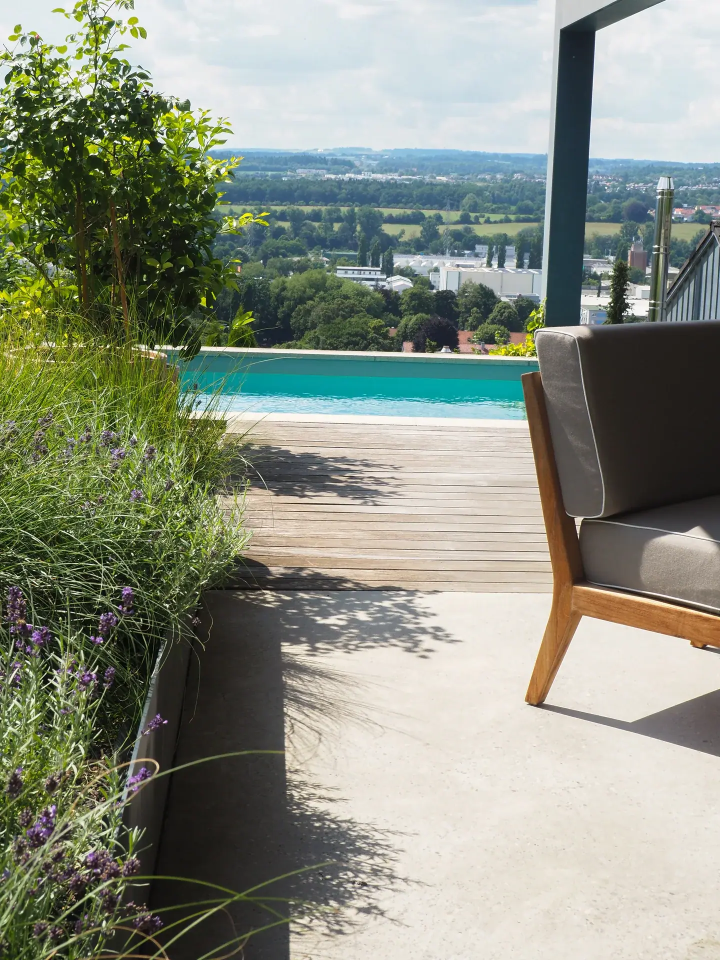 Poolterrasse mit Holzdeck, Lounge-Sofa und Lavendelbeet mit weitem Blick über die Landschaft