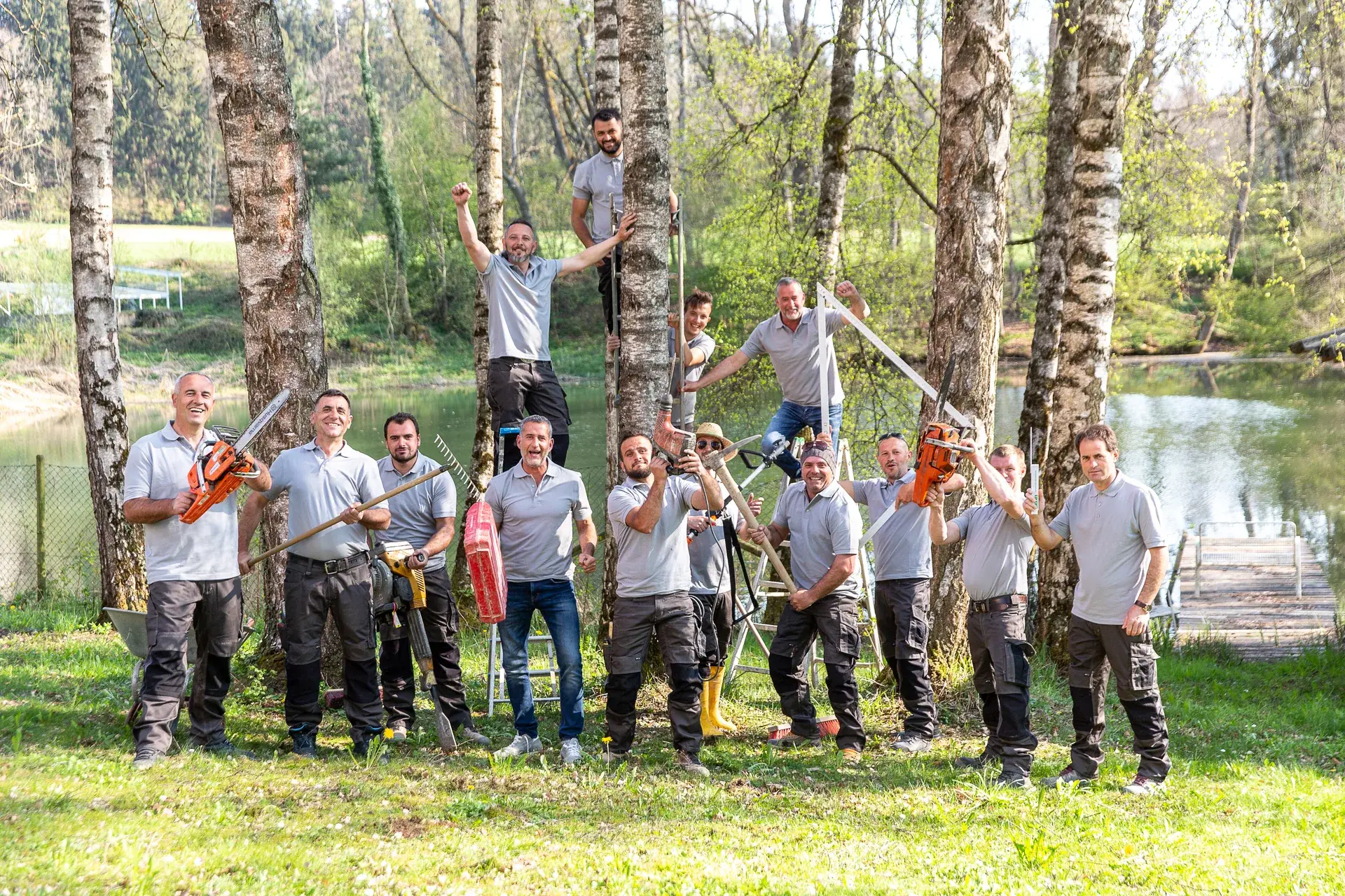 Das Team von WohnraumGarten mit Gartengeräten zwischen Birken am Wasser
