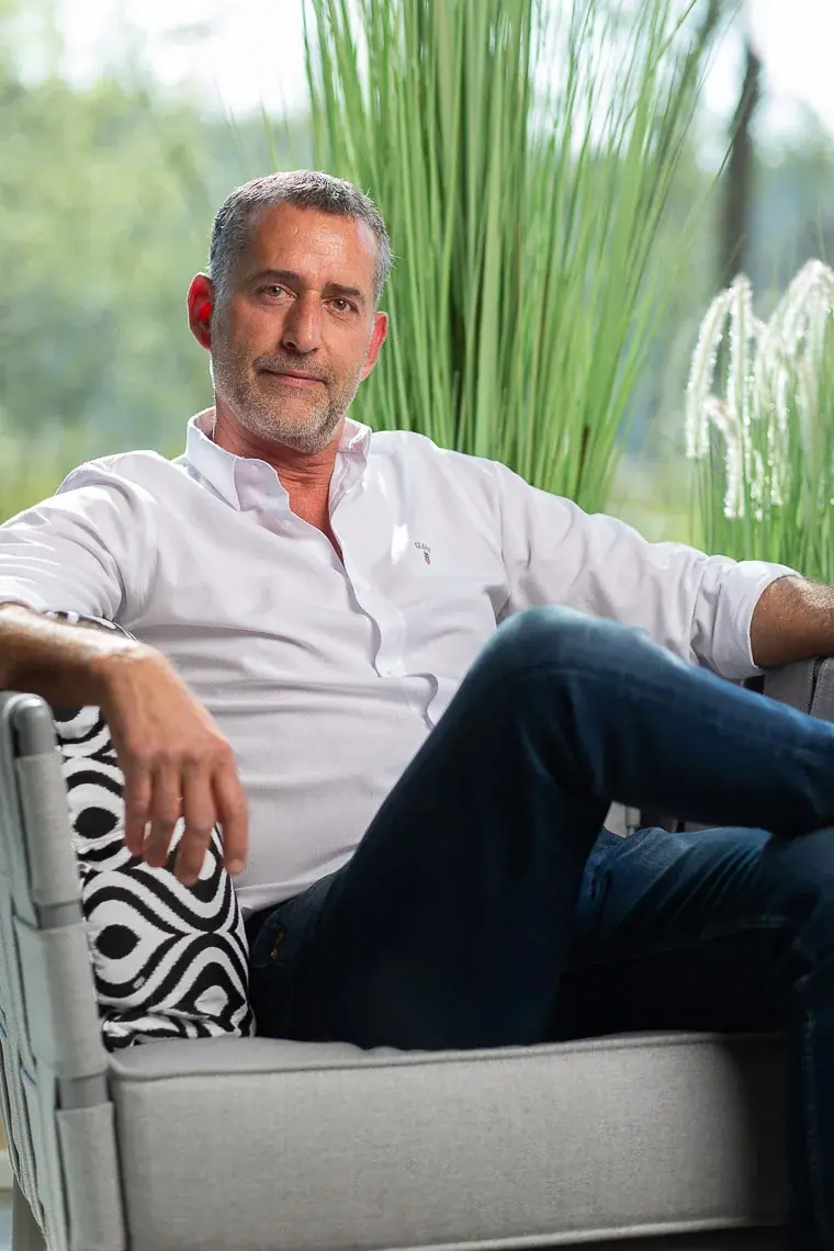 Andreas Liewig, entspannt auf einem grauen Gartensofa vor Ziergräsern