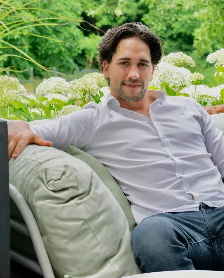 Luca Liewig, entspannt auf einem Gartensofa vor weißen Hortensien