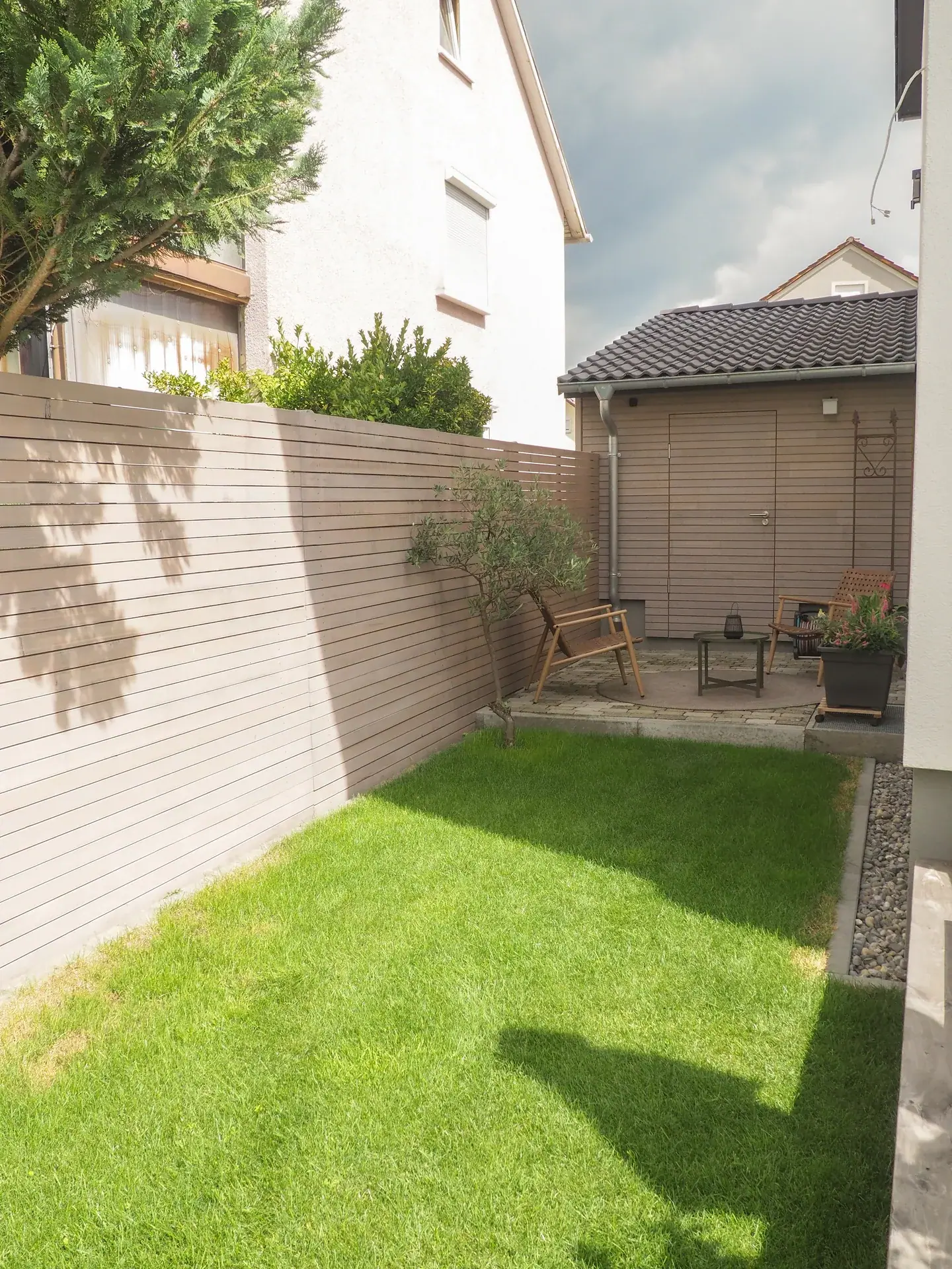 Kleiner Garten mit Sichtschutzwand und Rasenfläche.