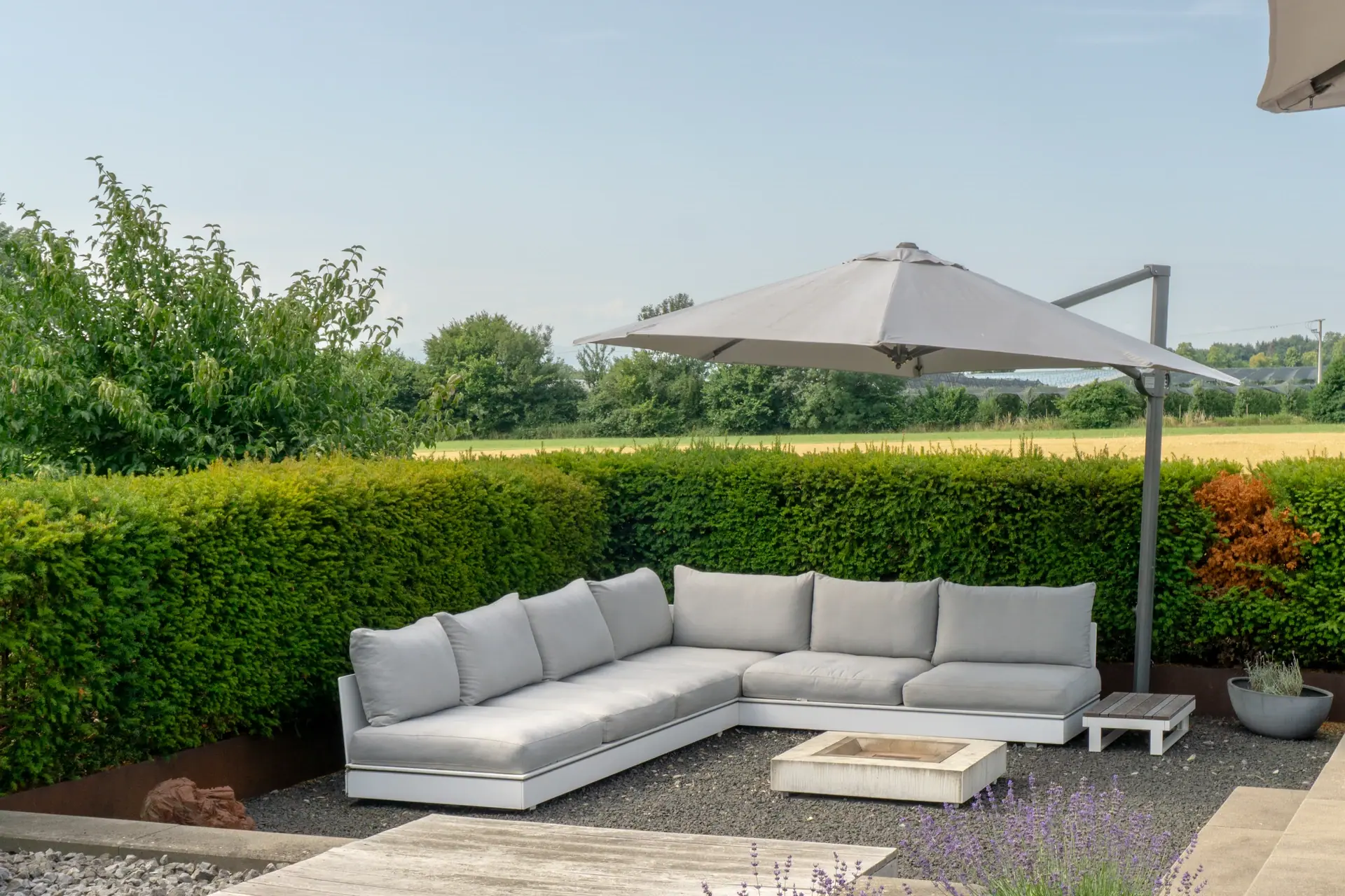 Helle Ecklounge vor einer dichten Hecke.
