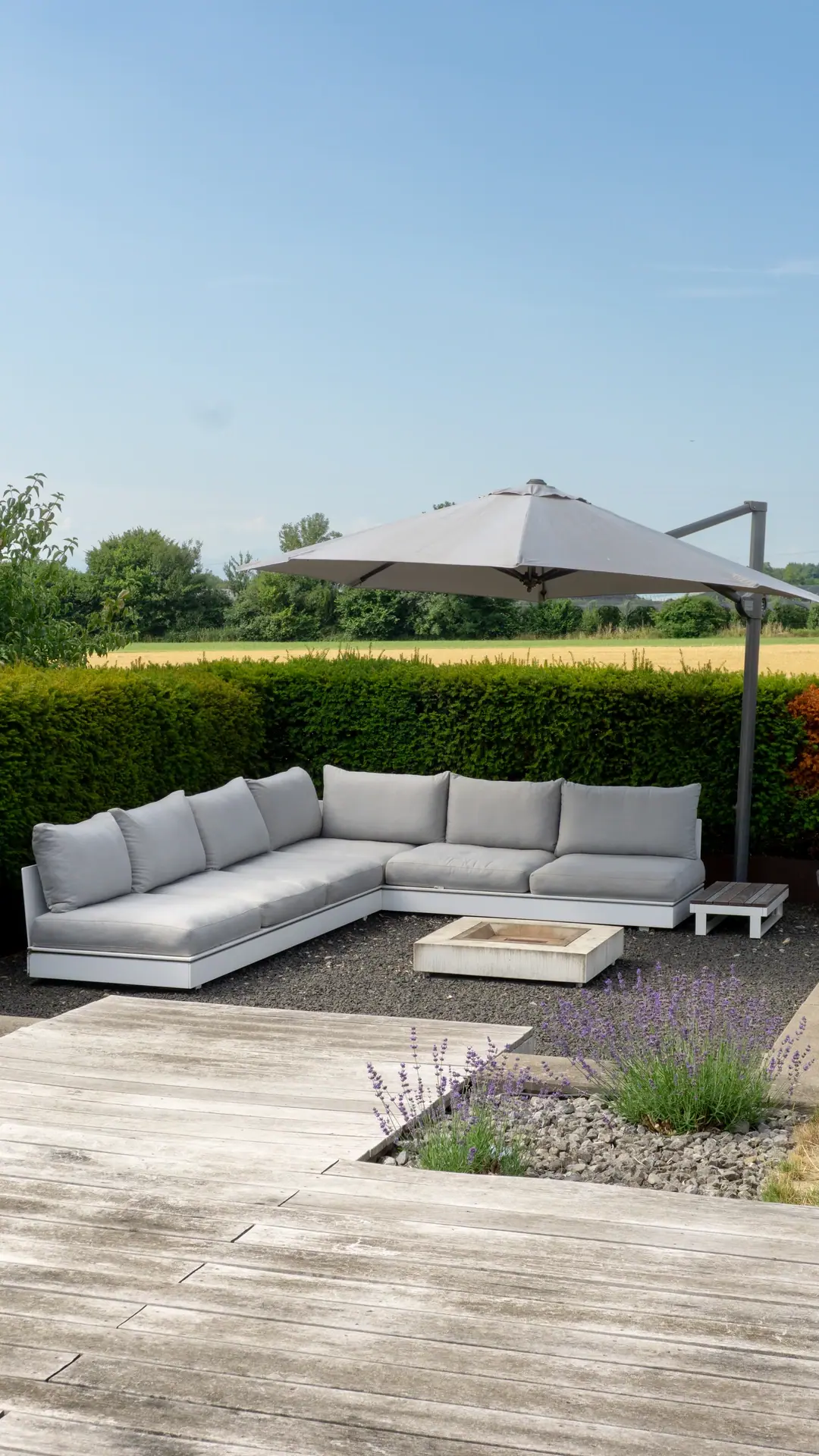 Helle Gartenlounge mit Schirm und weitem Blick auf die Landschaft.