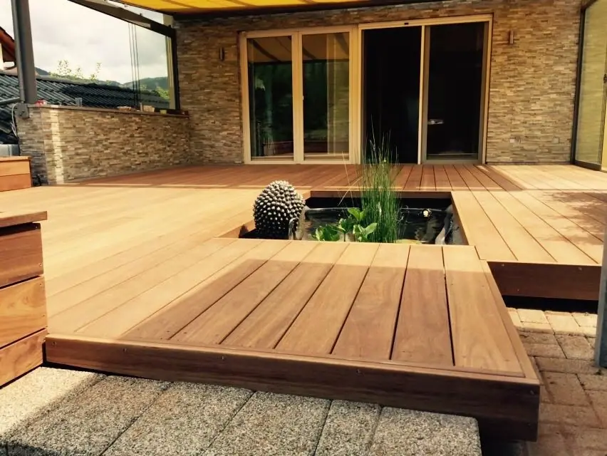 Holzdeck mit eingelassenem Wasserbecken vor einer Hausfassade.