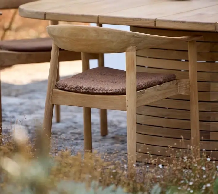 Detail eines Holzstuhls an einem Gartentisch.