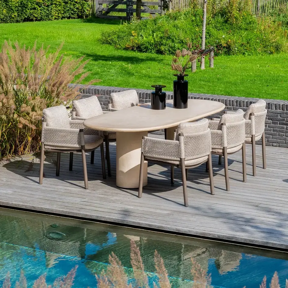 Holztisch mit Stühlen auf einer Terrasse am Pool.
