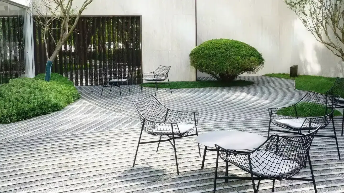 Sitzgruppe aus Metall auf einem Holzdeck im Garten.
