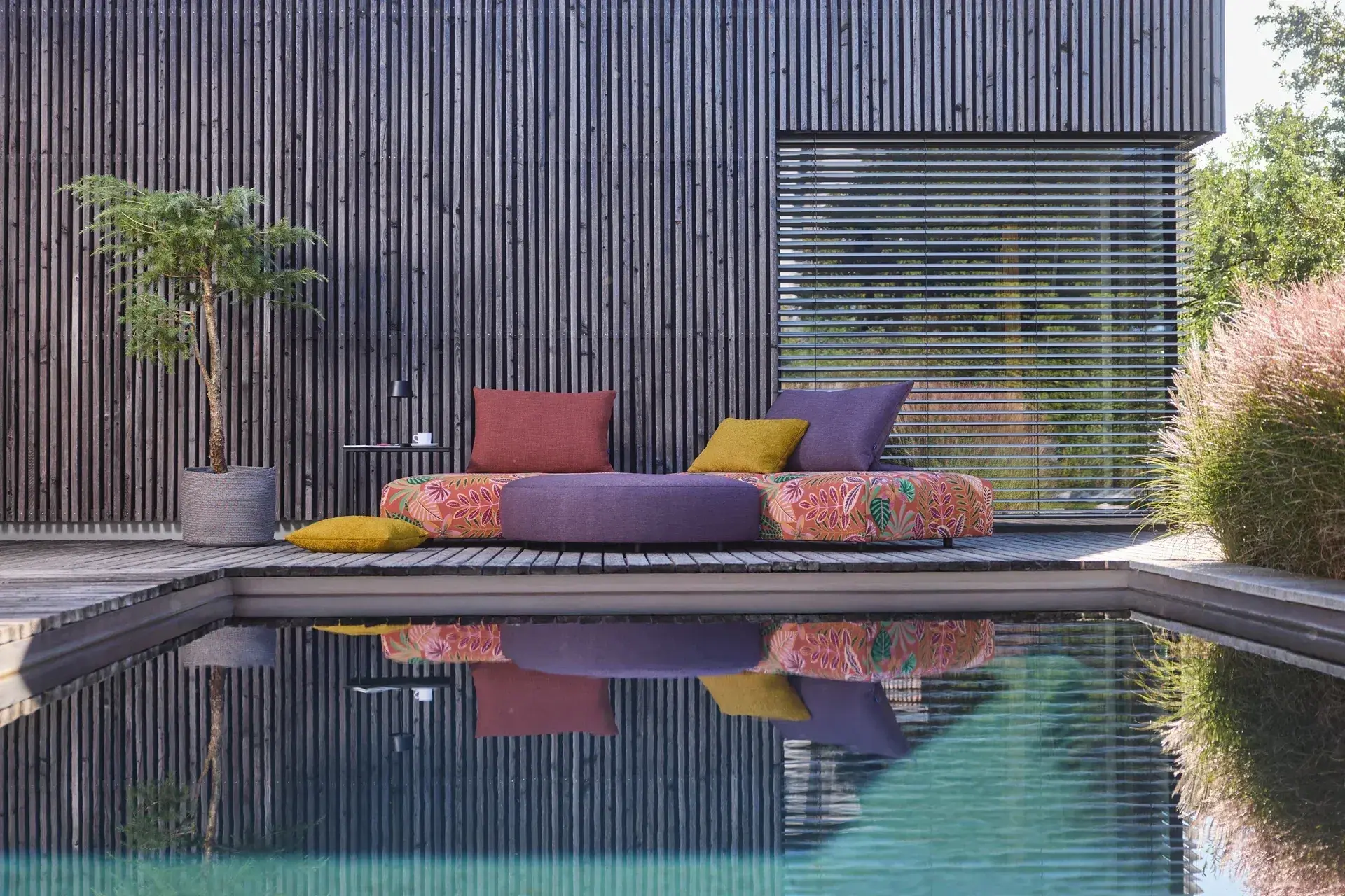 Farbiges Outdoorsofa auf einer Terrasse am Pool.