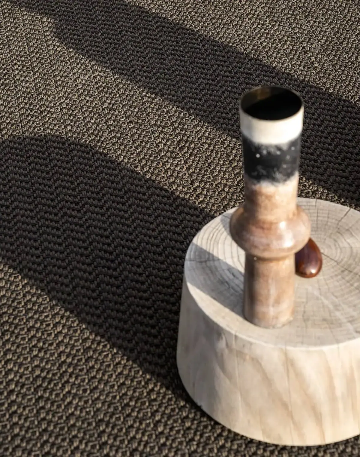 Detail eines gewebten Teppichs mit kleinem Gefäß.