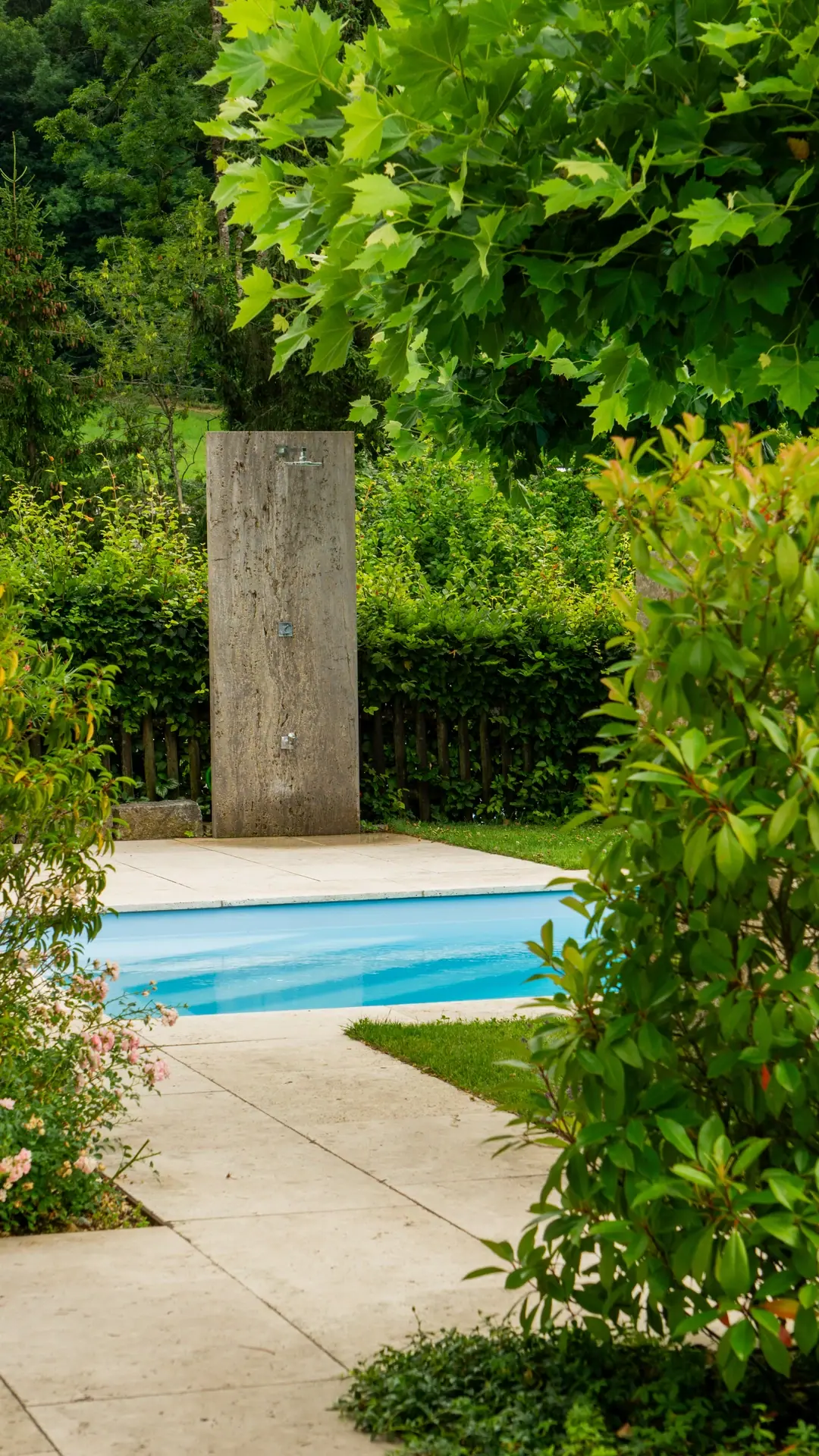 Pool zwischen hohen Hecken und Bäumen.