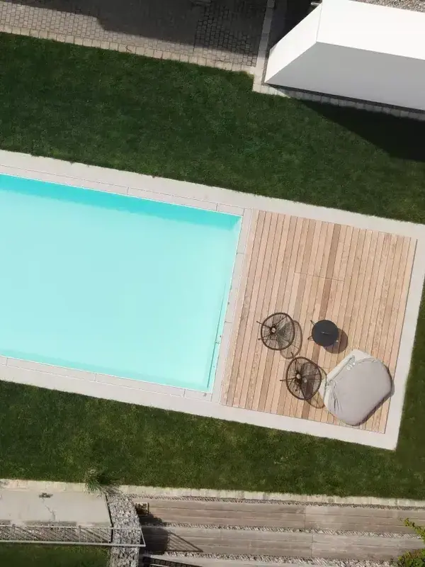 Luftaufnahme eines Pools mit Holzdeck und Sitzmöbeln.