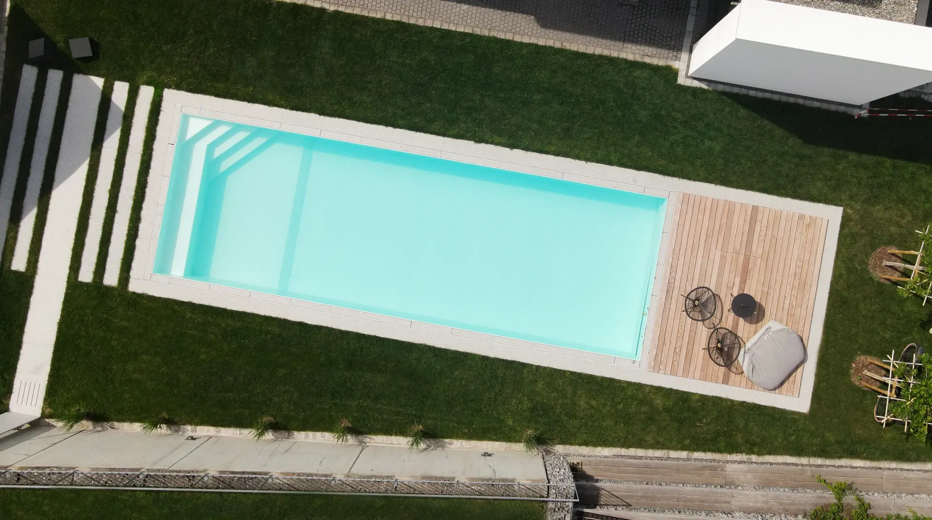 Luftaufnahme eines Pools mit Holzdeck und Rasen.