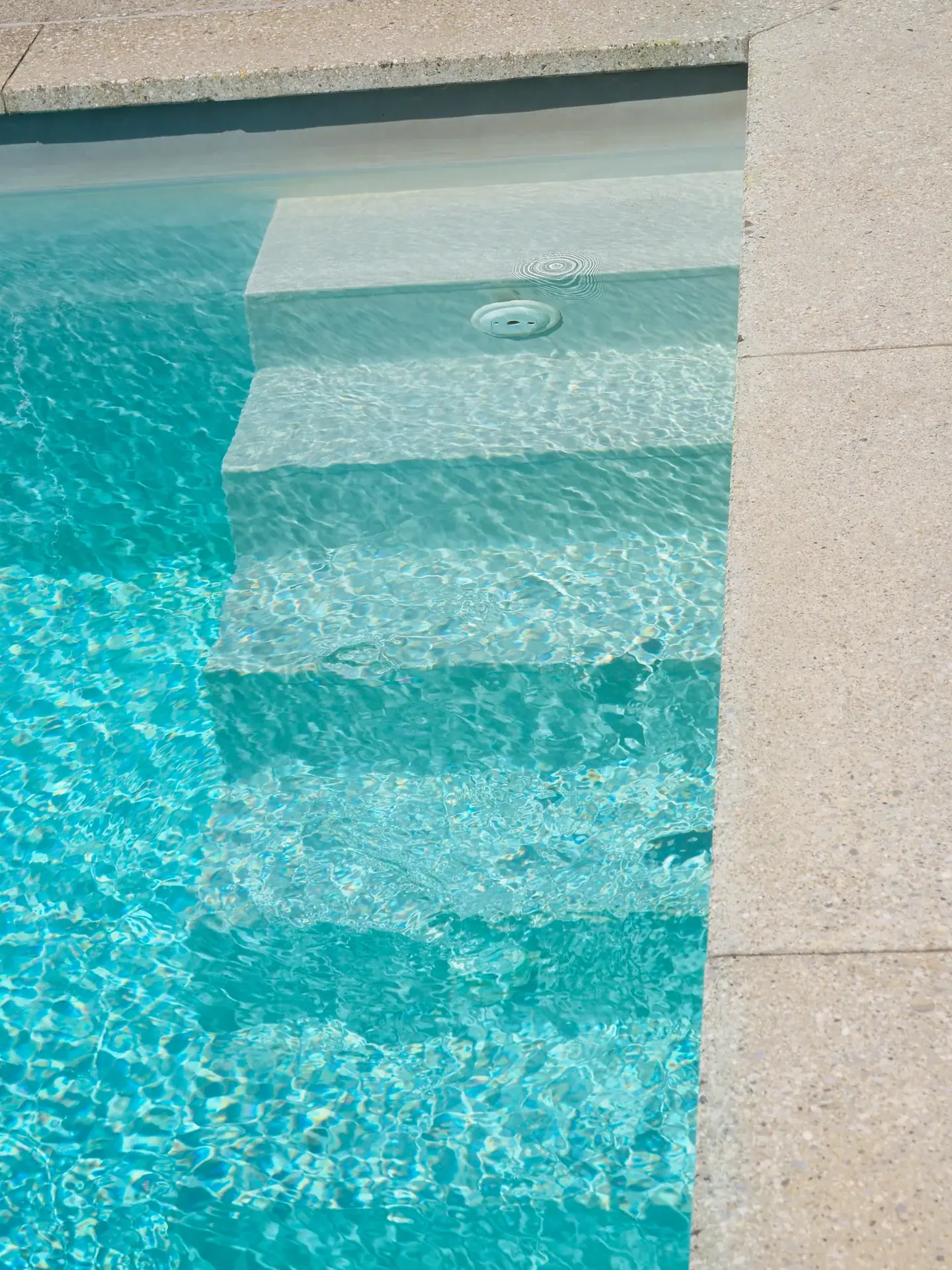 Treppenstufen im türkisfarbenen Poolwasser.