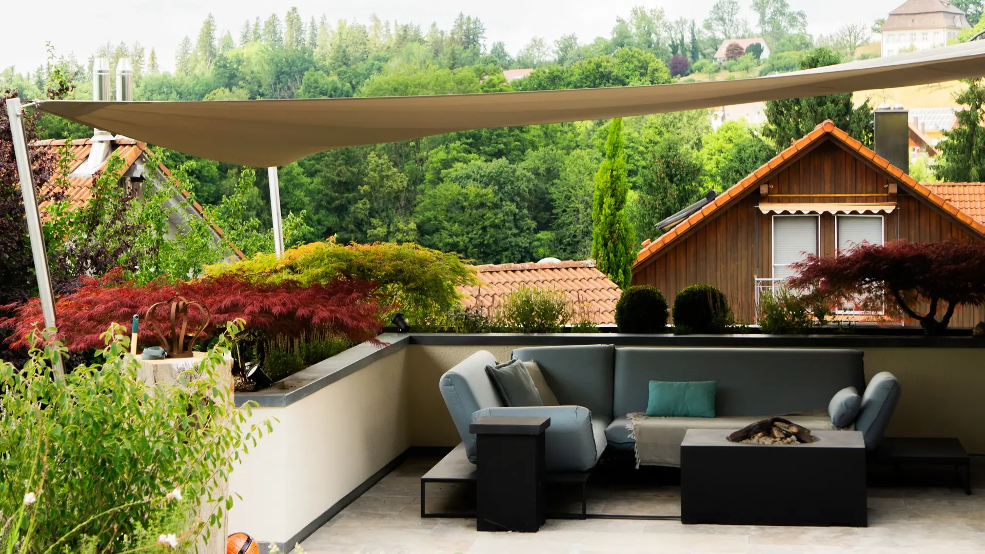 Sonnensegel über einer dunklen Gartenlounge.