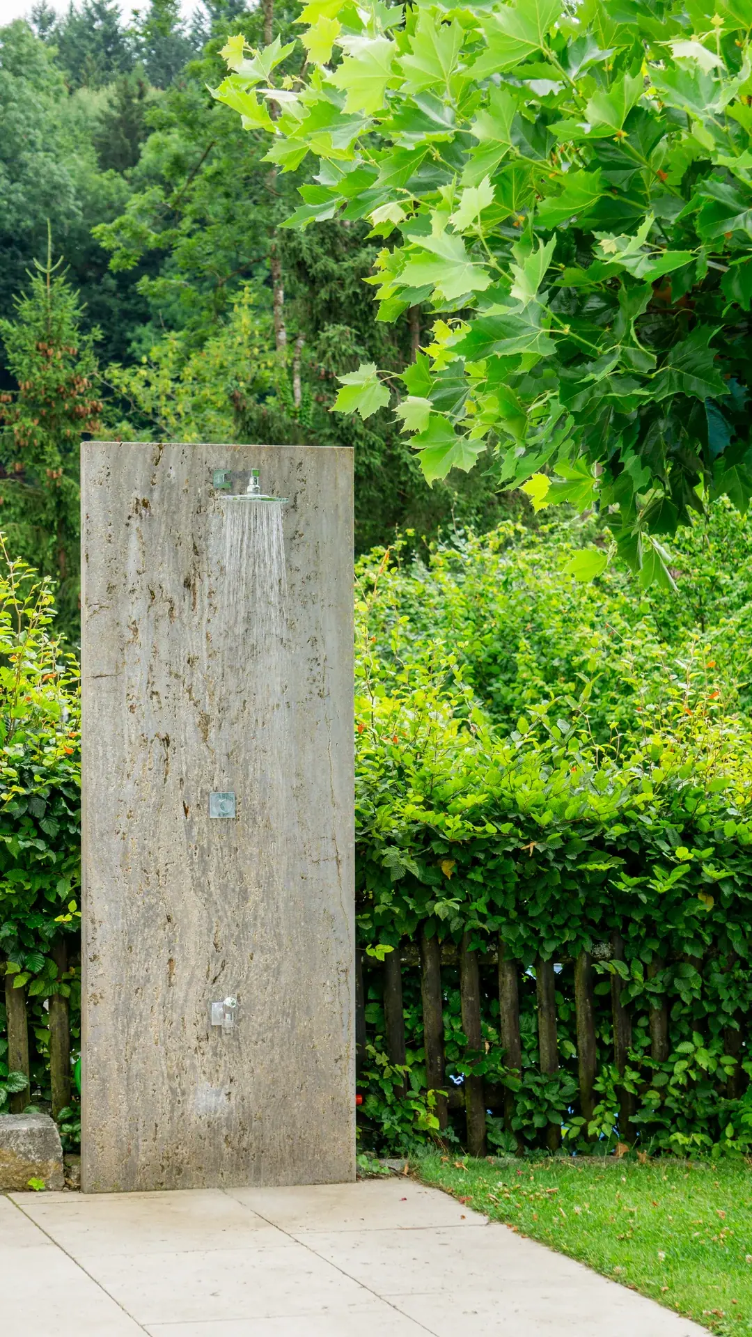 Schlanker Steinpfeiler in einem grünen Garten.