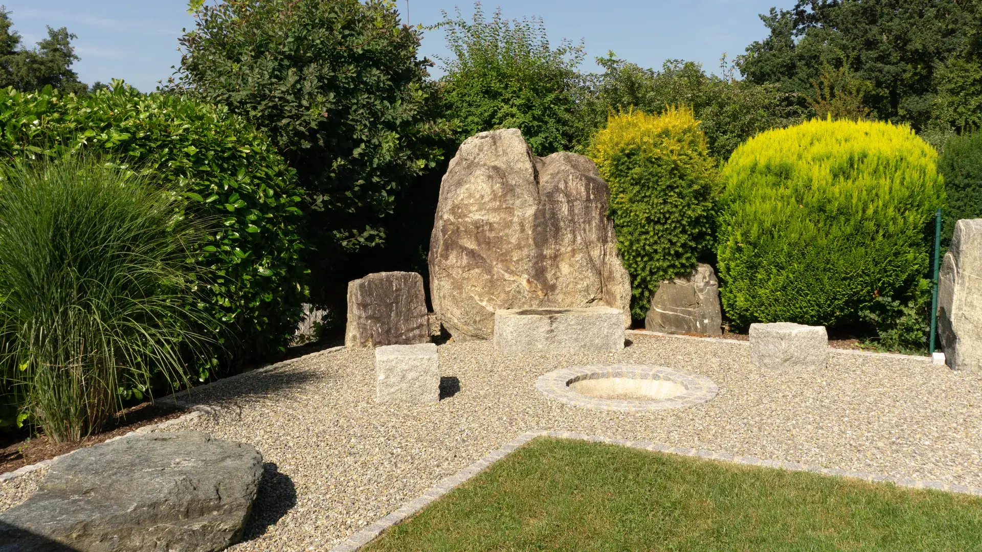 Große Steinskulptur auf einer Kiesfläche im Garten.