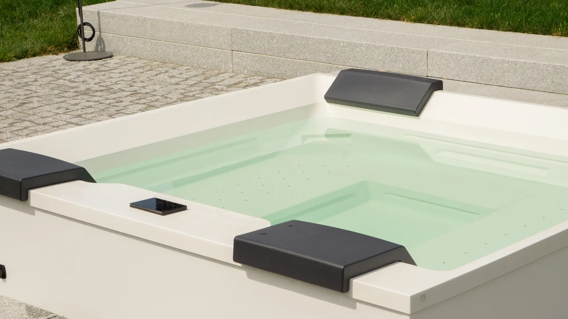 Whirlpool mit hellen Wänden und dunklen Kopfstützen.