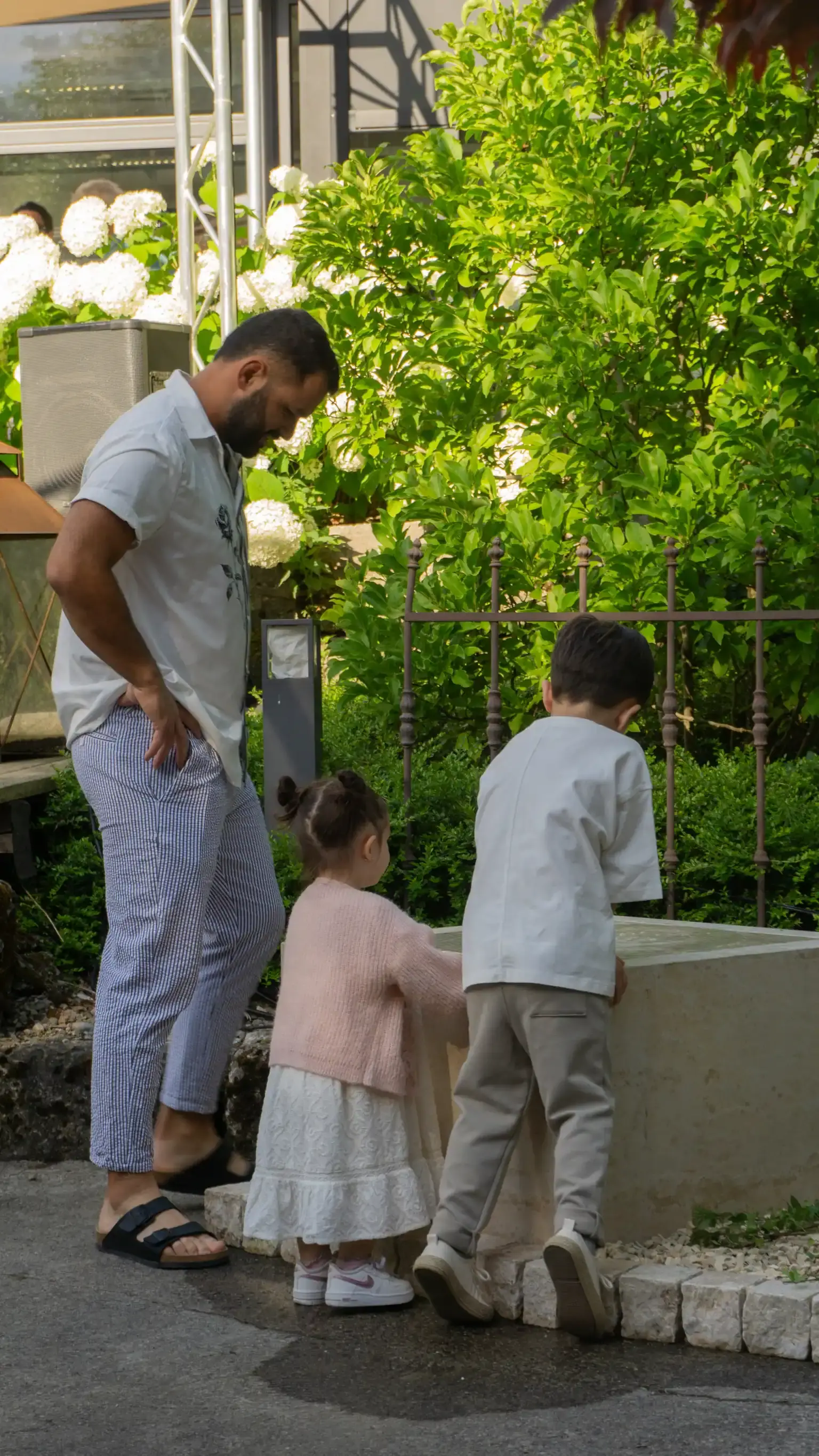 Kinder spielen beim Jubiläumsfest an einem Gartenbrunnen aus Naturstein